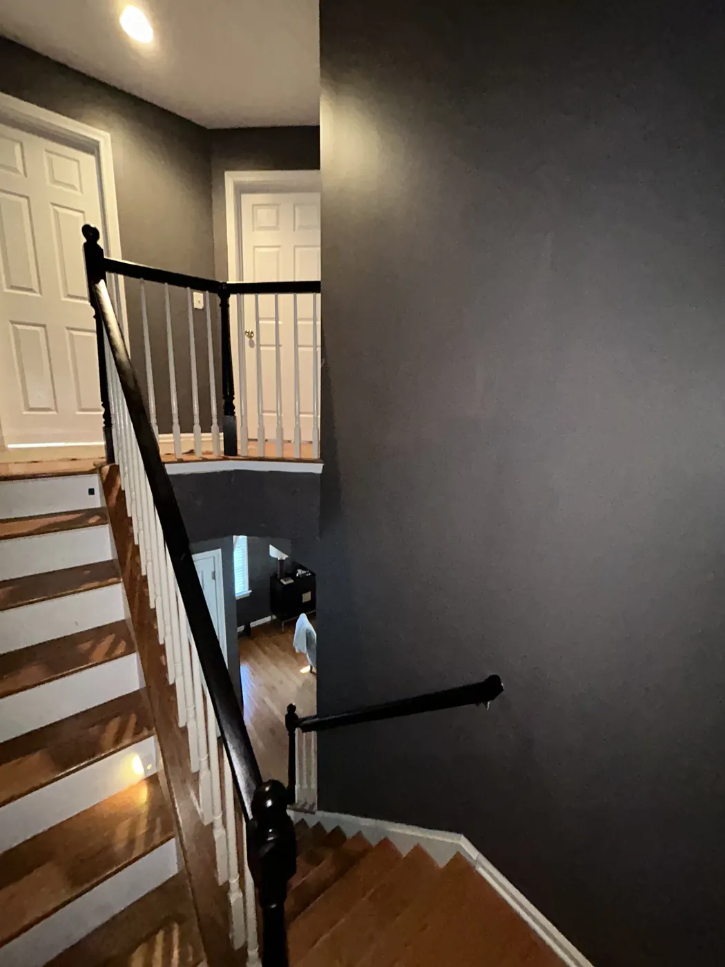 Freshly painted dark gray stairwell with black railing and white balusters